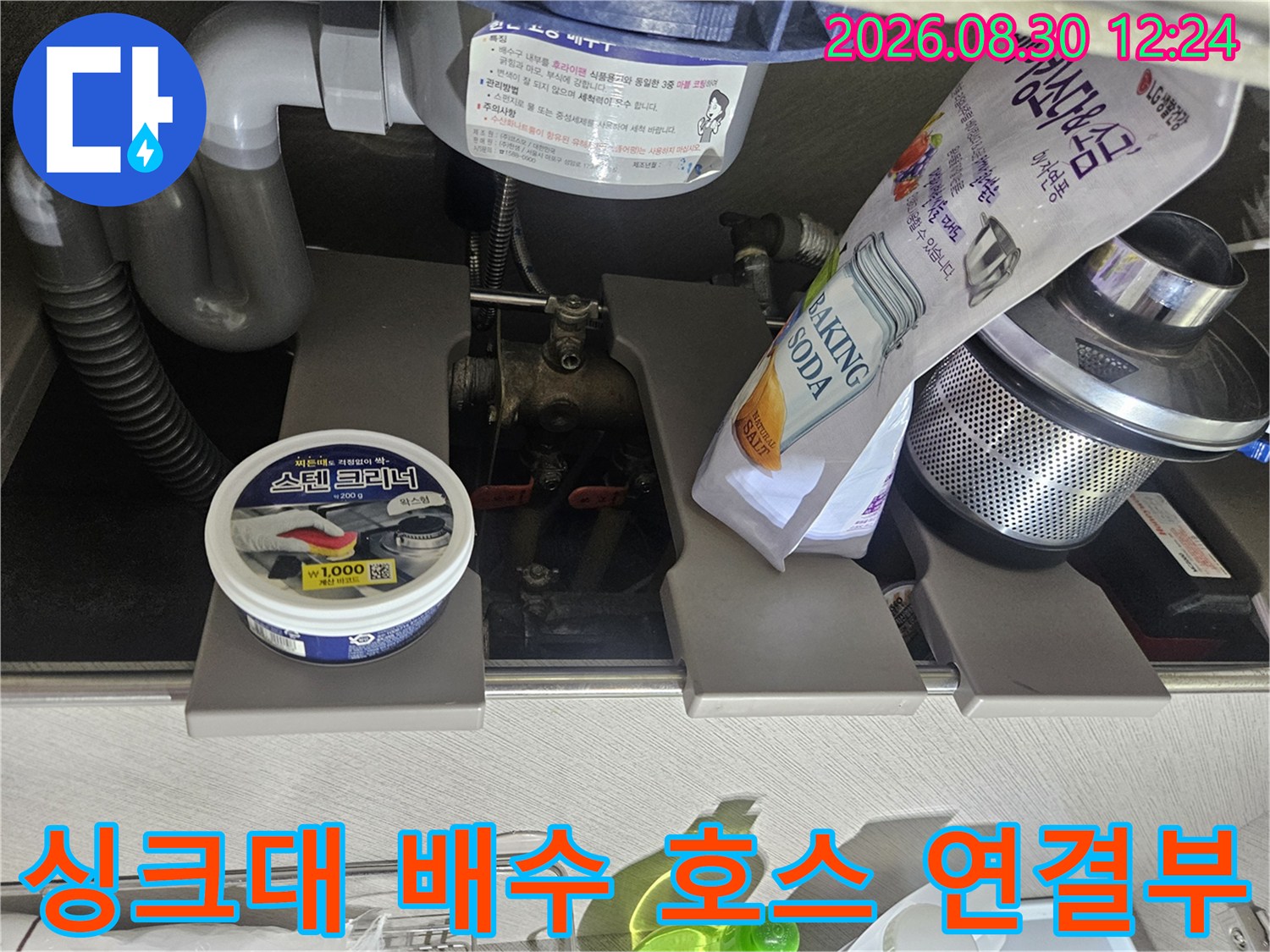 싱크대 하부장 내부의 굴곡진 배수 호스와 연결 마감재를 보여주는 이미지입니다.