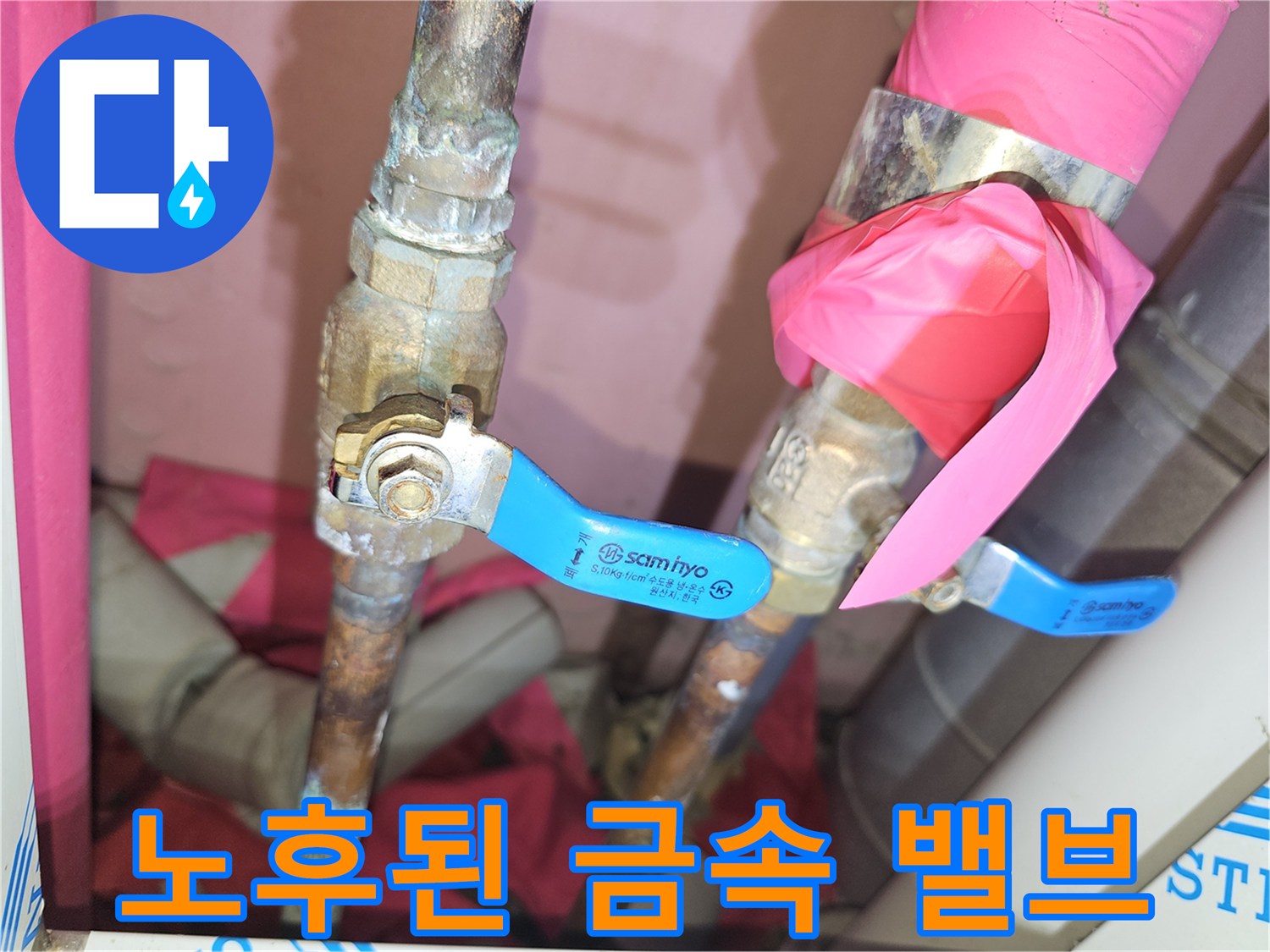 분홍색 보온재가 감겨 있는 노후 배관과 파란색 레버 밸브