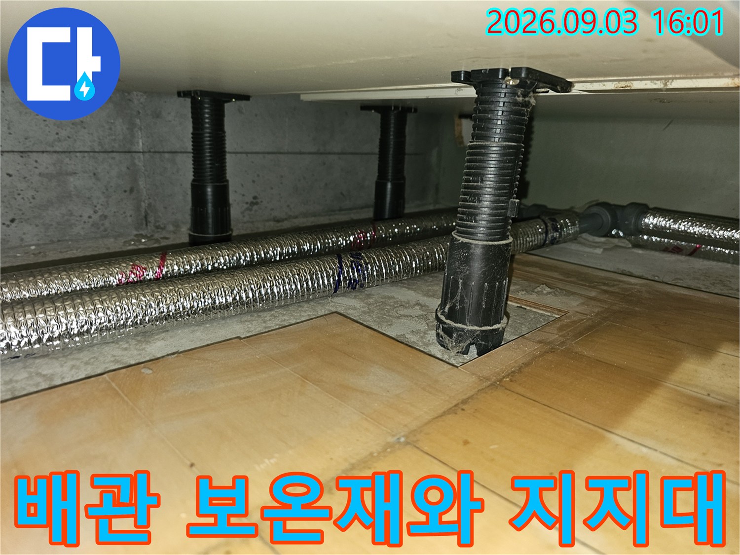 은색 은박 보온재가 감겨있는 배관과 검은색 수직 지지대의 모습