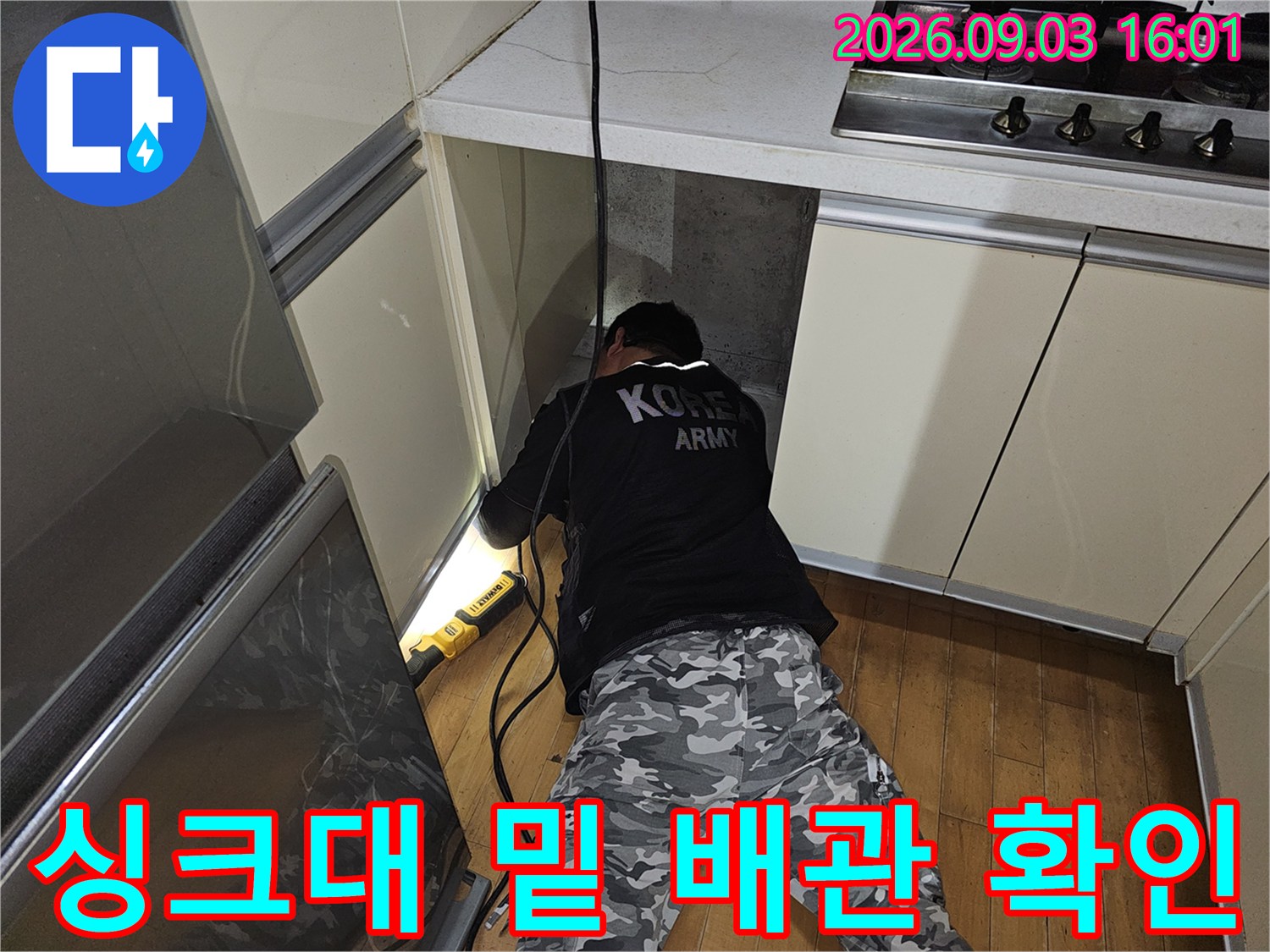 좁은 싱크대 하단 공간에서 배관의 이상 유무를 점검하는 작업 장면입니다.