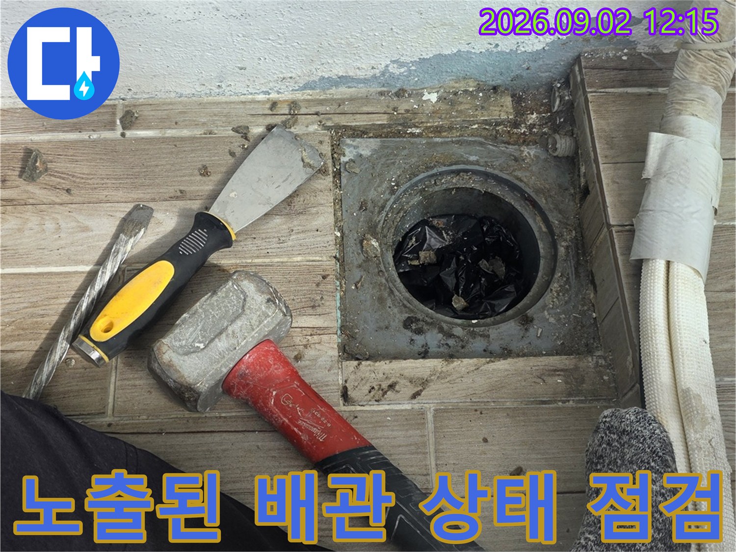 타일 아래 드러난 배관 연결 부위의 결함을 확인하는 작업 과정입니다.