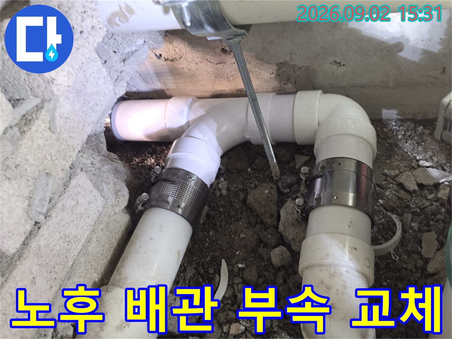 균열된 하수 배관을 제거하고 - 금속 클램프로 고정하여 보수 중인 장면입니다.