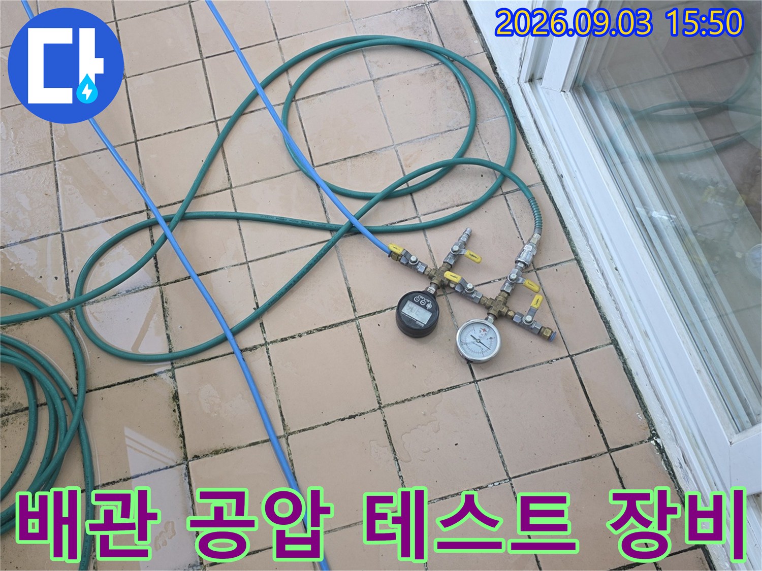 베란다 타일 바닥에 설치된 배관 압력 측정 장치와 호스