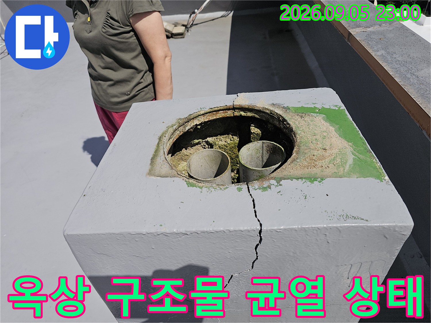 배관이 설치된 옥상 구조물의 갈라진 틈을 근접 촬영하였습니다.