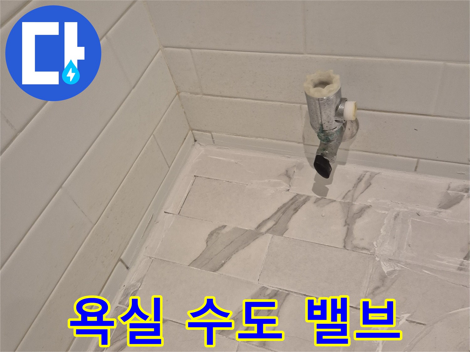 벽면 타일 벽에 돌출된 급수용 밸브와 배관 모습