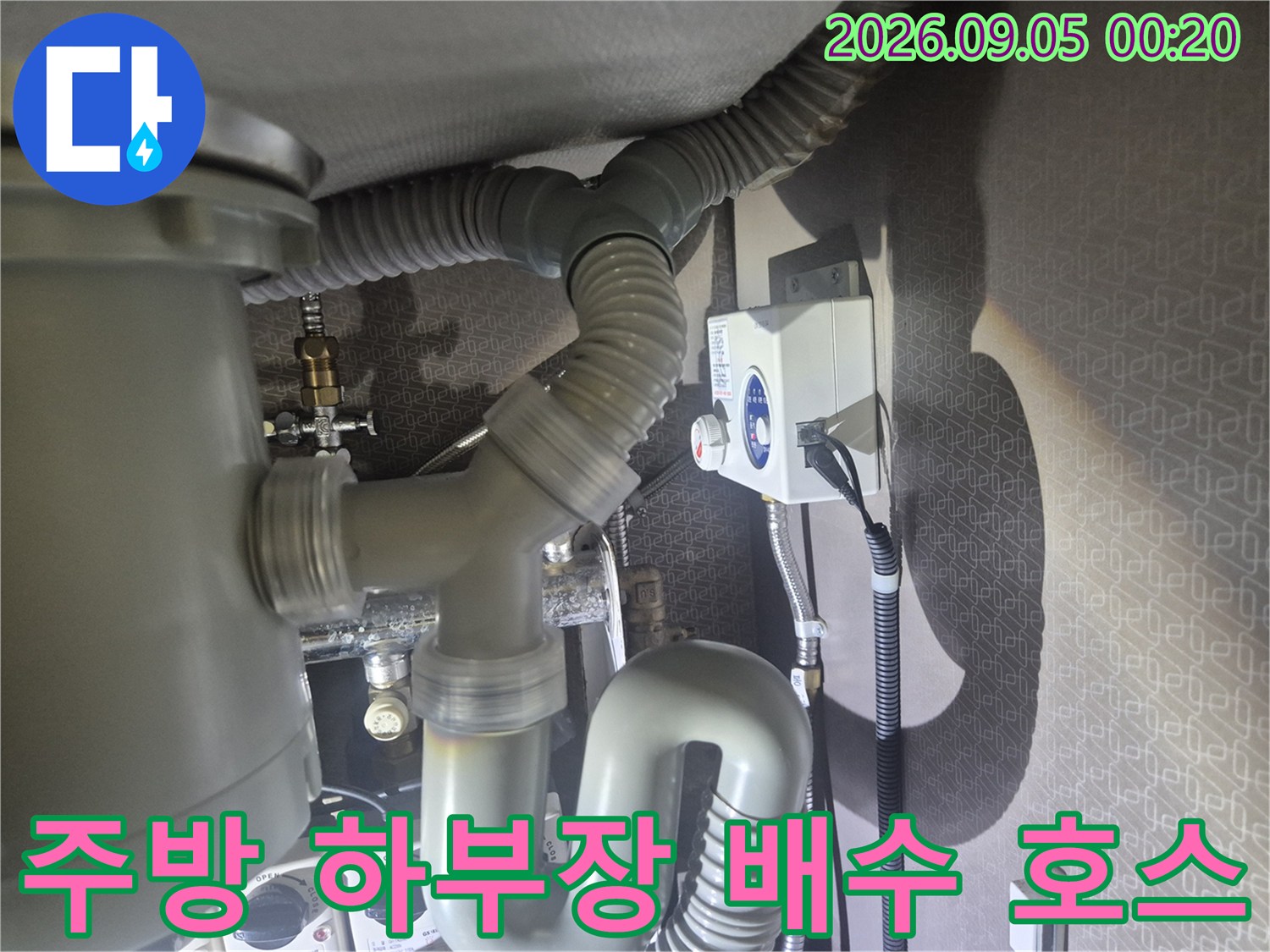 싱크대 아래쪽의 굵은 회색 주름관과 벽면 배관 연결 부위 상세 사진입니다.