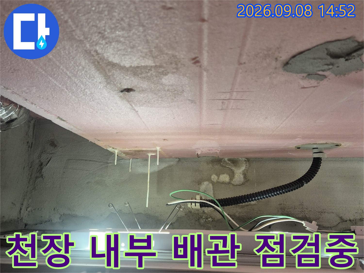 점검구로 본 천장 내부의 검은색 배관과 전기선 및 벽면