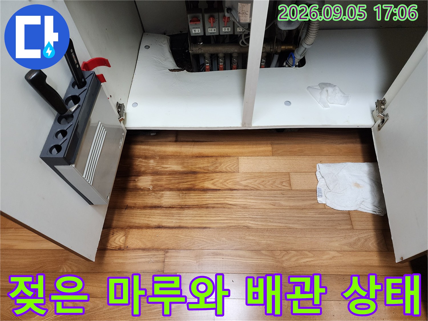 싱크대 하부장 바닥의 젖은 마부와 노출된 배관 연결부