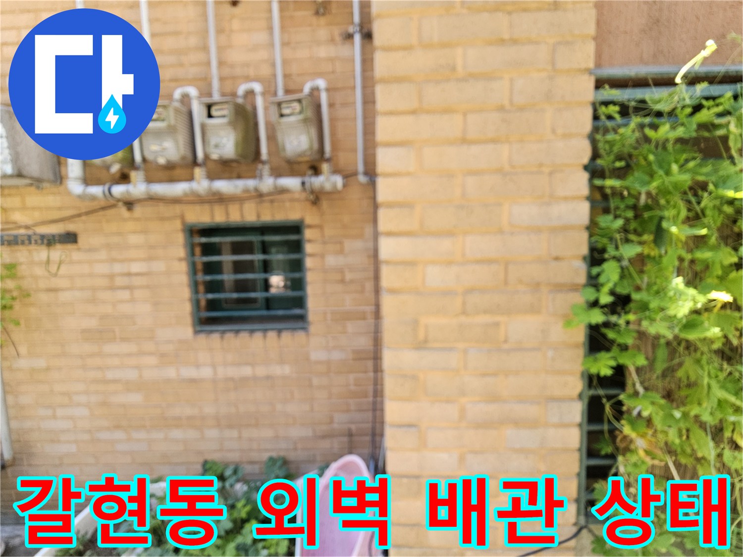 벽돌 벽에 고정된 수도 계량기와 연결 배관의 모습