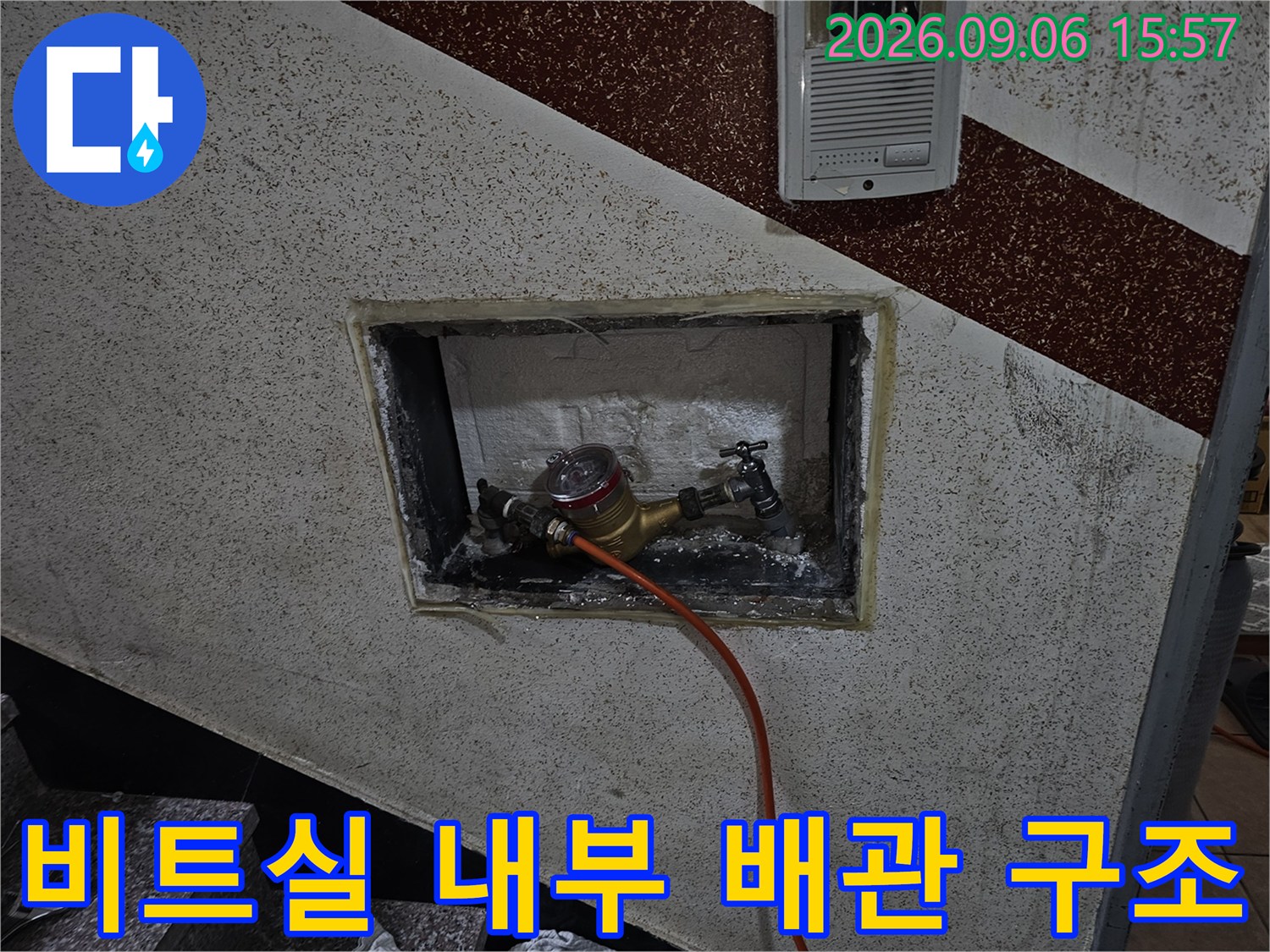벽면 타공 부위 속에 보이는-수도 계량기와 연결된 배관들