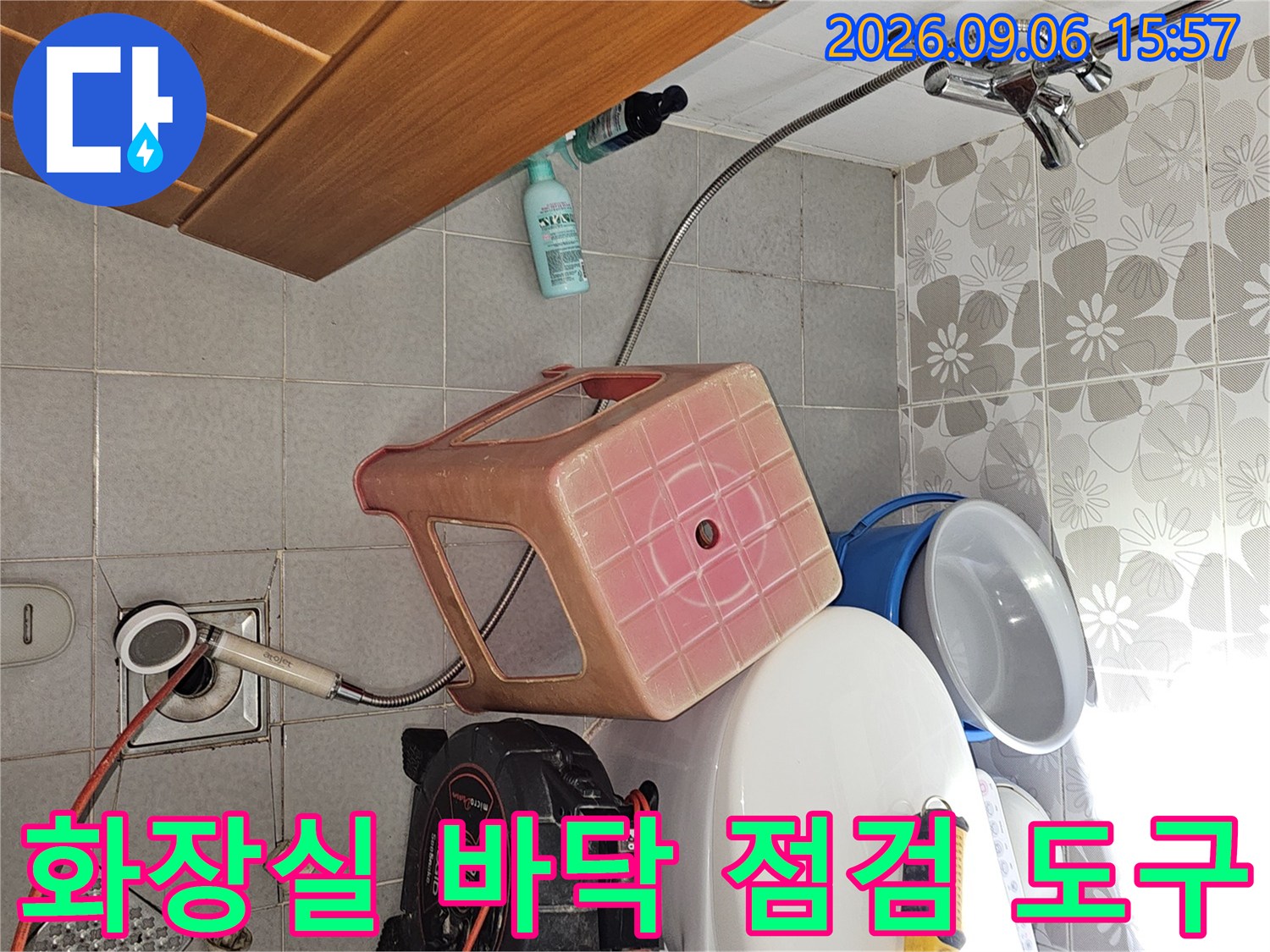 화장실 변기 옆에 배치된 누수 진단용 압력계와 전동 드릴 작업 환경
