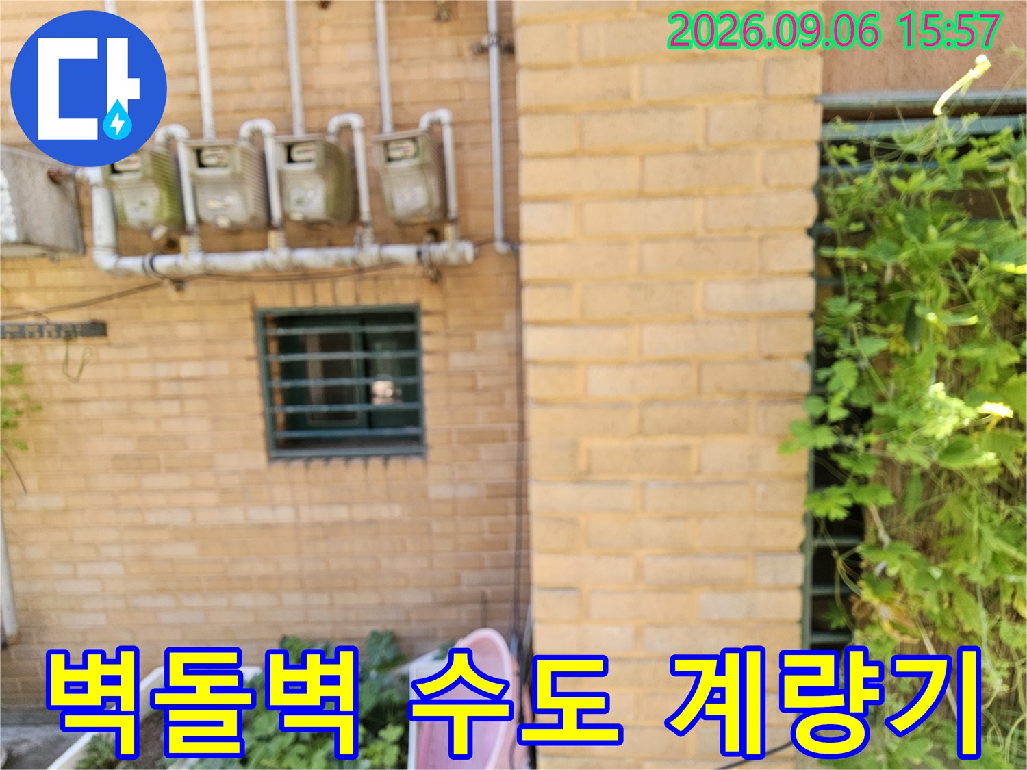 황토색 벽돌 벽면에 설치된 네 개의 수도 계측 장치와 배관들