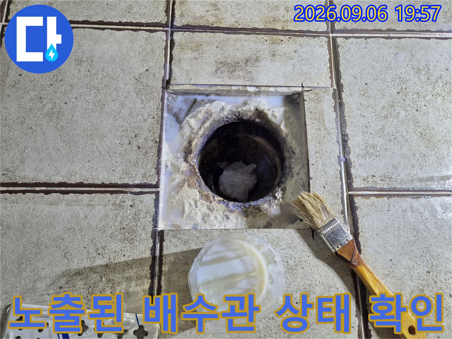 탈거된 배수구 주변의 오염된 타일과 노출된 하수 배관 모습입니다.