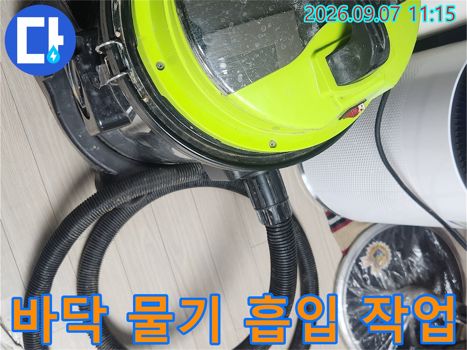 석션기를 사용하여 장판 아래 고여 있는 물을 빨아들이는 현장 모습입니다.