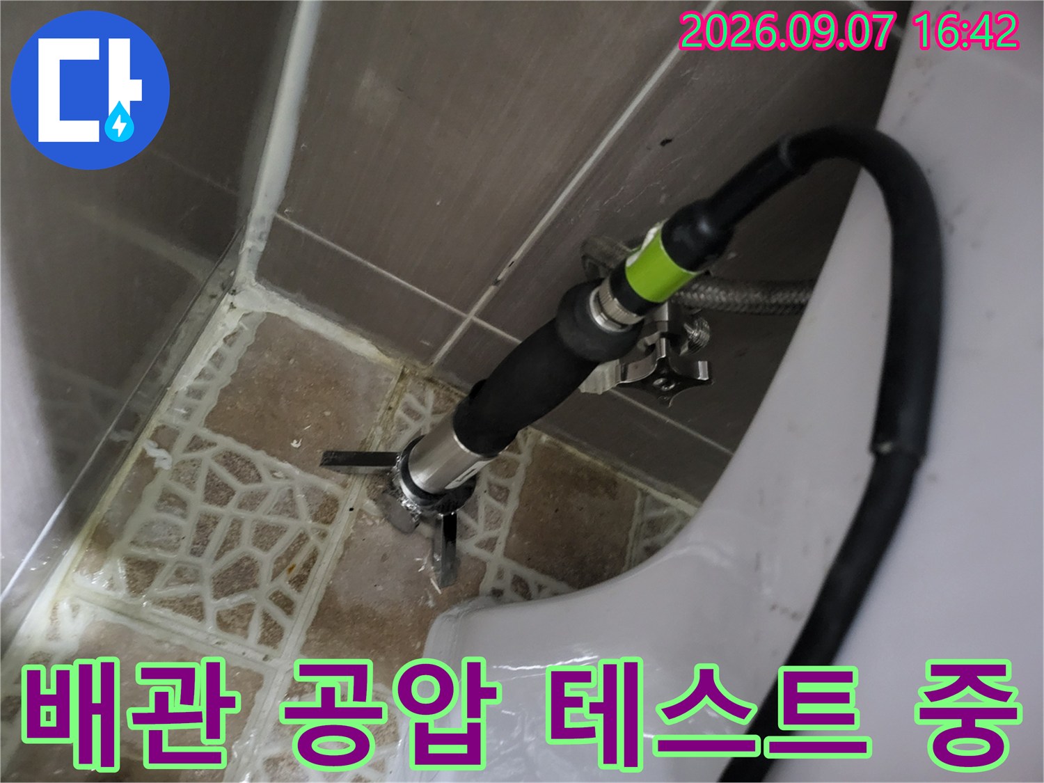 화장실 변기 주변 배관에 가스 탐지 장비를 연결하여 누수 지점을 찾는 모습입니다.