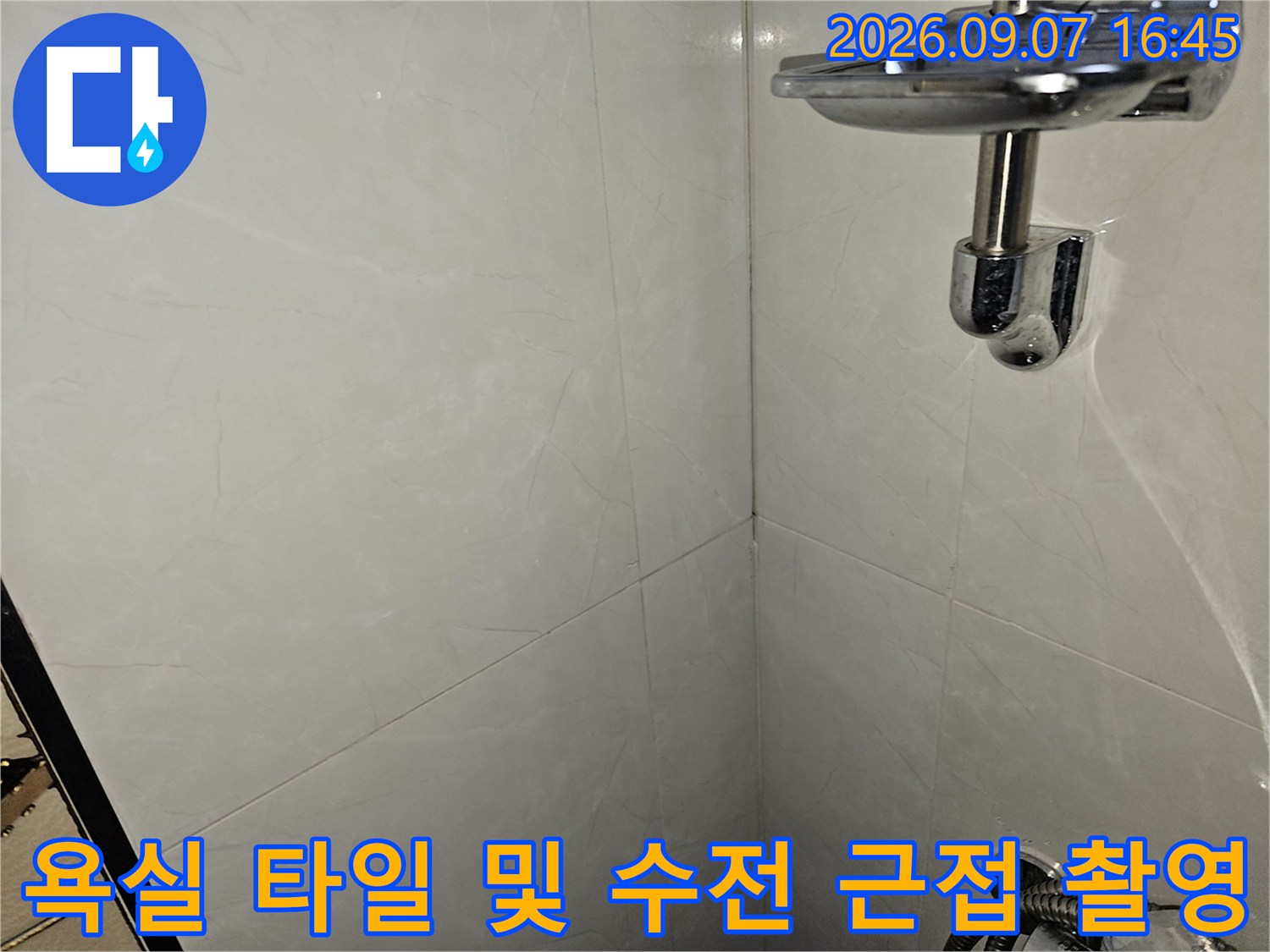 밝은색 대리석 패턴 타일과 샤워기 수전 부위 상세 사진