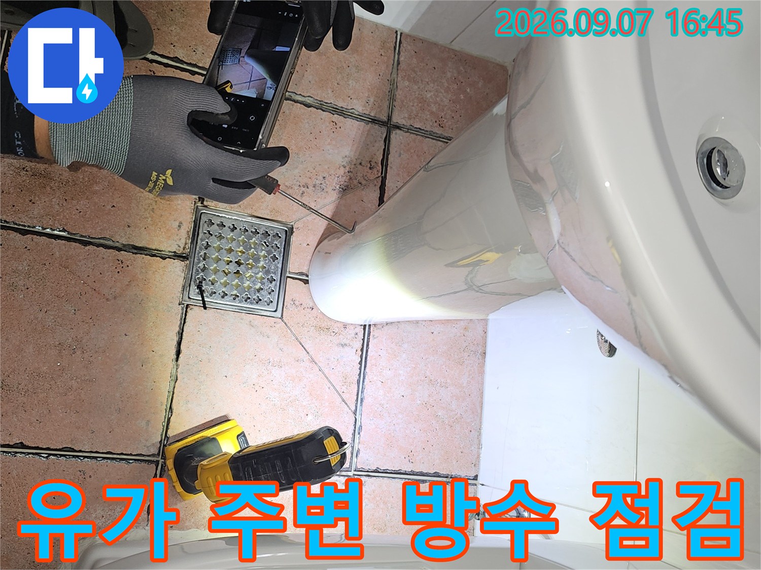손전등으로 비춘 화장실 배수구 유가의 틈새와 타일 상태
