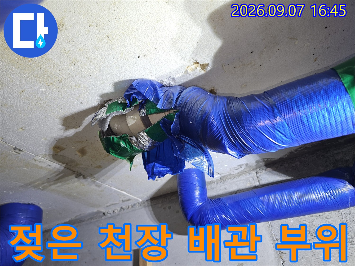 콘크리트 천장의 얼룩과 파란색 보온재 배관의 접합부를 촬영한 사진입니다.