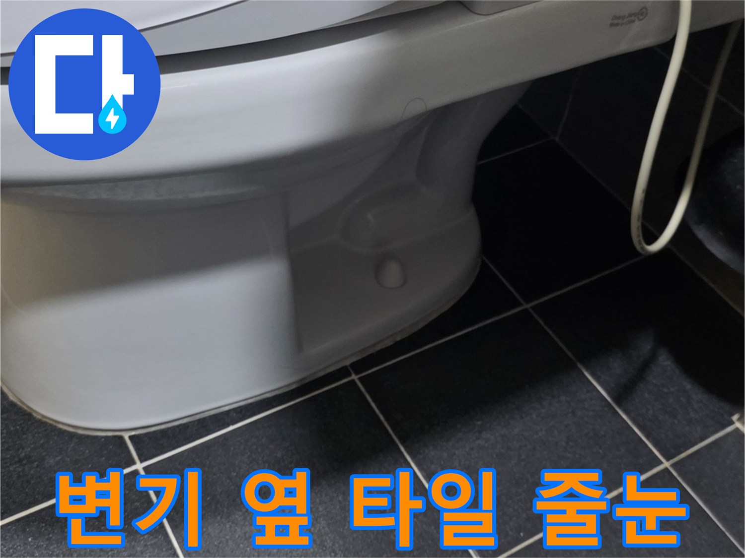 어두운 회색 타일과 변기 하단부의 접합 부위 사진