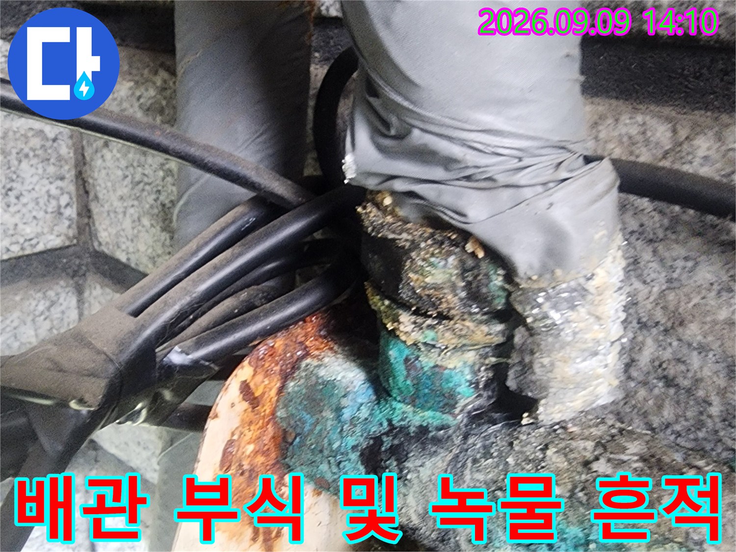 부식된 배관 연결부와 주변의 녹물 자국 상세 사진