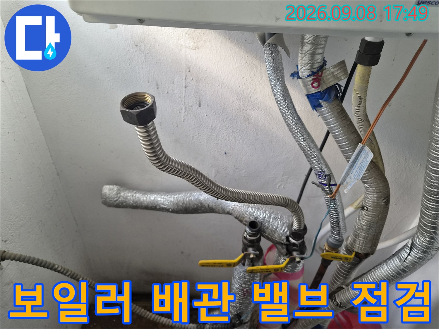 노란색 밸브와 은색 보온재 배관의 연결부를 근접 촬영한 사진입니다.