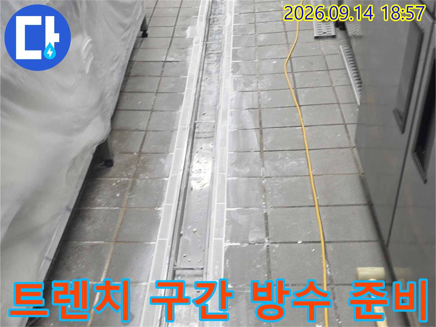 배수 트렌치를 따라 타일을 제거하고 하부 층을 드러낸 공사 현장입니다.
