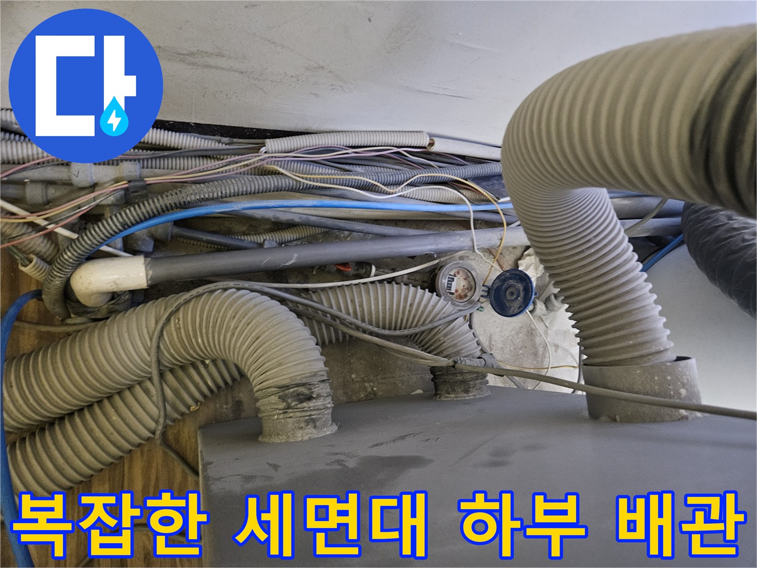 세면대 아래쪽의 굵은 주름관과 작은 급수 호스들이 연결된 모습