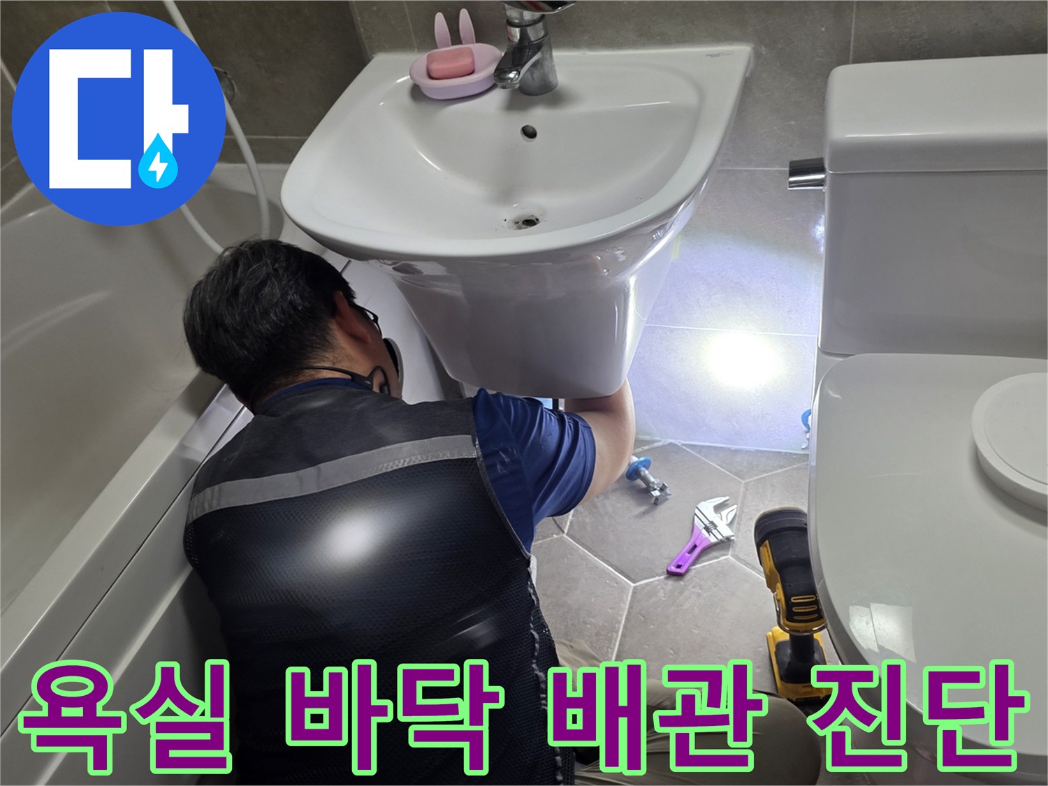 몽키스패너와 공구를 사용하여 세면대 하부 배관을 점검합니다.