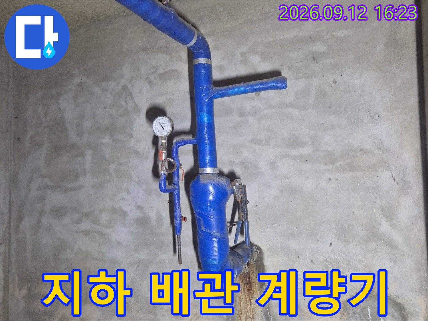 지하 시설물에 설치된 수도 계량기와 파란색 보온 배관