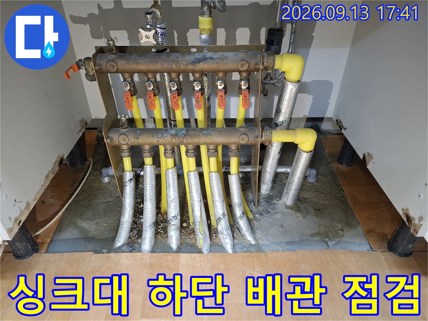 분배기와 노란색 배관이 복잡하게 연결된 싱크대 내부 모습입니다.