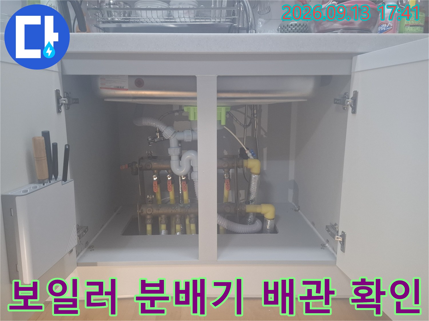 싱크대 하부의 보일러 분배기와 연결된 다양한 배관 및 부속들
