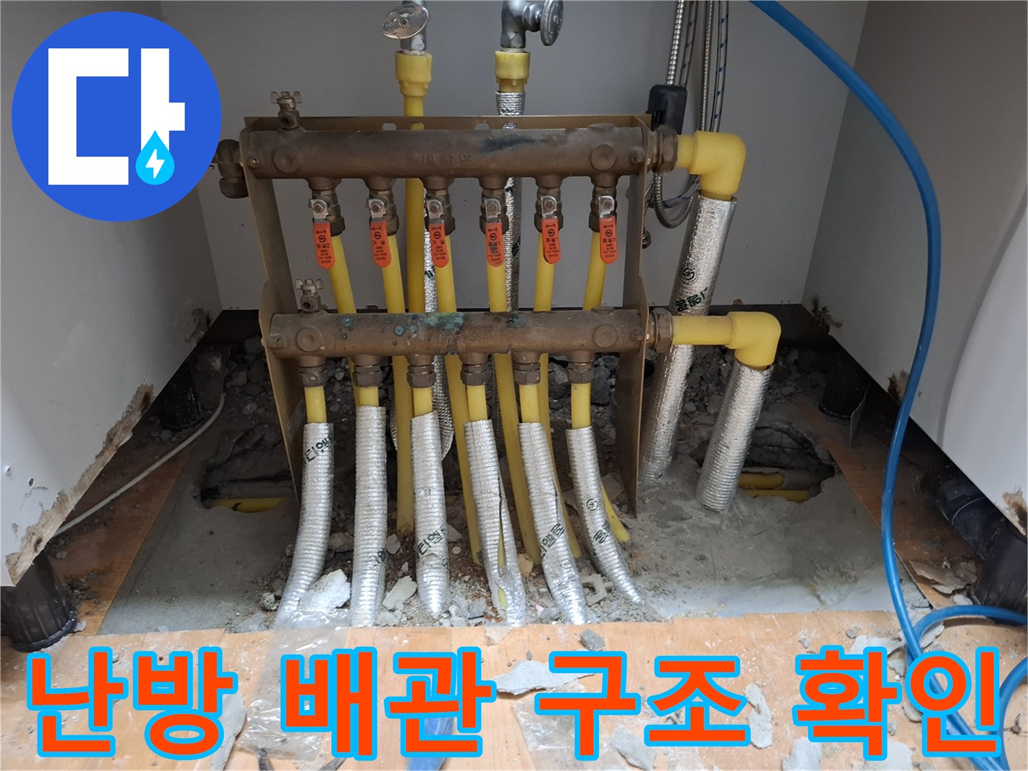 싱크대 하부의 복잡한 난방 분배기와 노란색 엑셀 배관 연결 상태