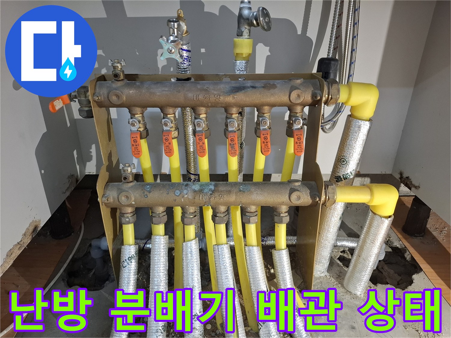 주방 싱크대 하단에 위치한 난방 분배기와 노란색 엑셀 배관의 연결 모습입니다.