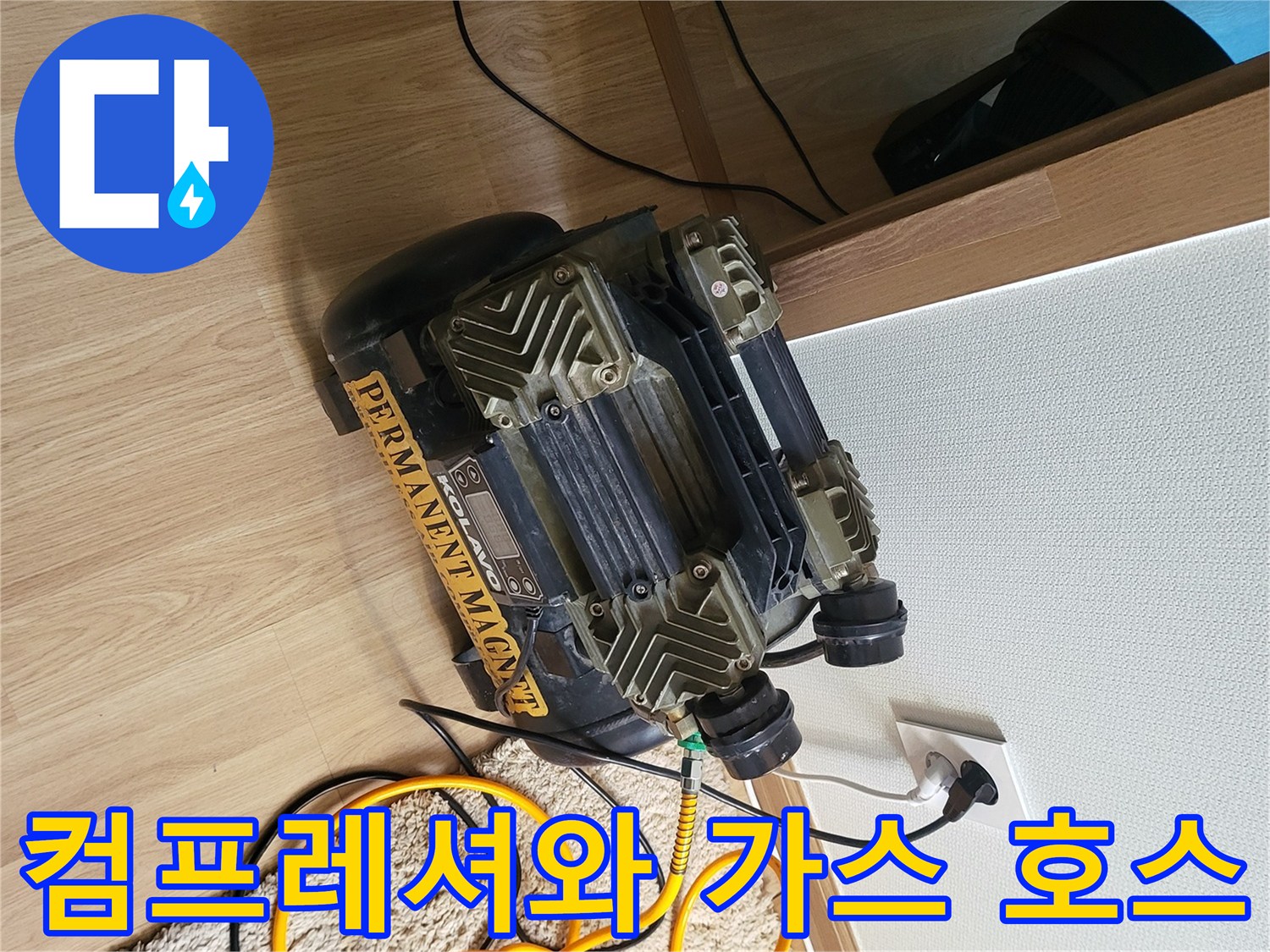 바닥에 설치된 공기 압축기와 노란색 배관 검사용 호스의 연결 모습