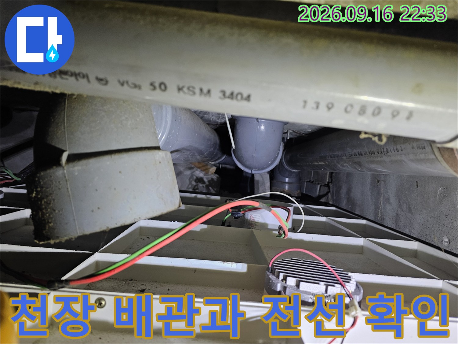 배관 아래로 지나가는 전기 배선과 구조물을 촬영한 사진입니다.